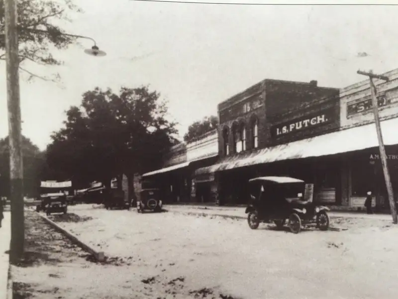 Historic photo of Main Street in Alachua, Florida, in 1910 with early cars and storefronts